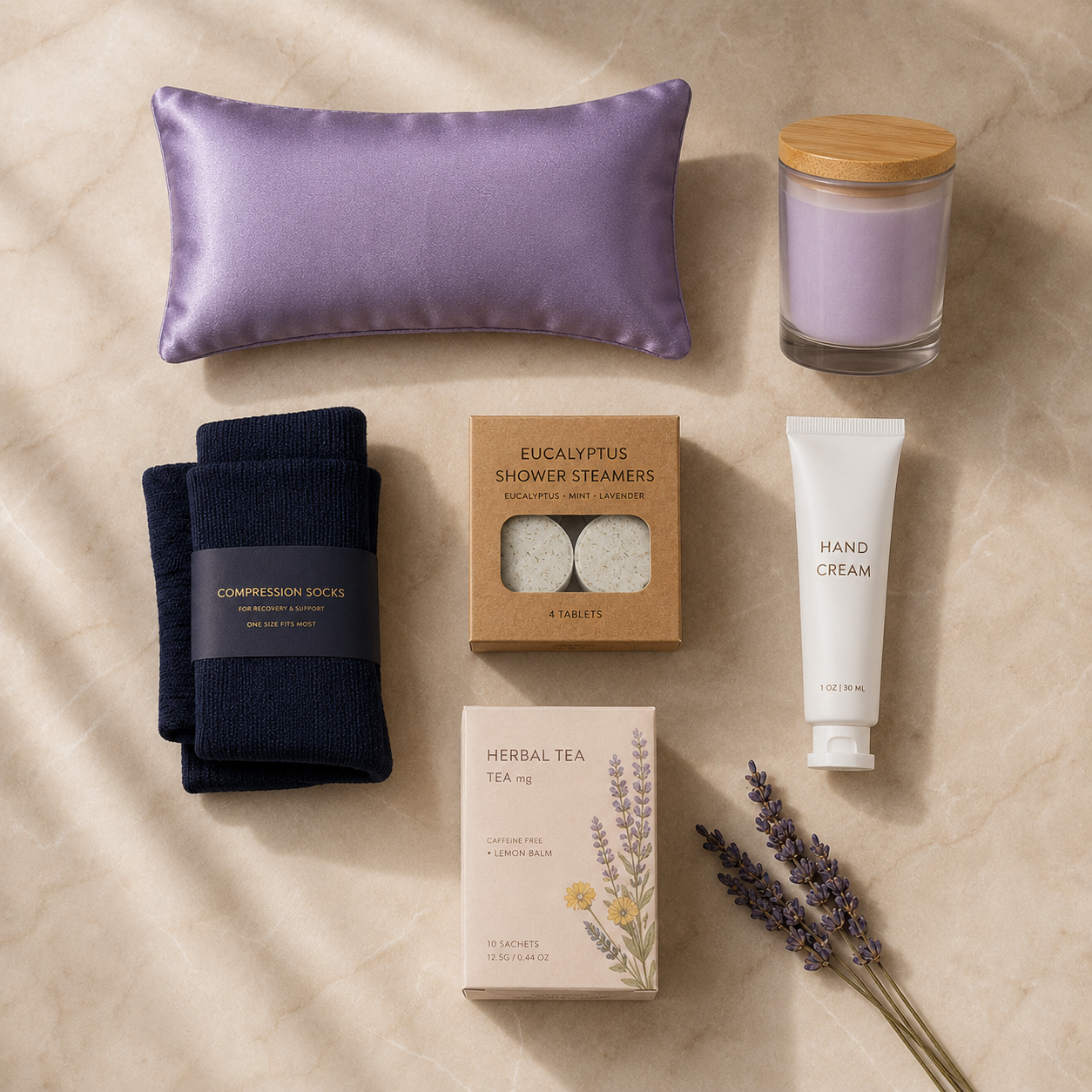 Flat-lay of Code Calm nurse recovery gift set contents on cream marble — lavender silk eye pillow, navy compression socks, eucalyptus shower steamers, hand cream, herbal tea and lavender soy candle