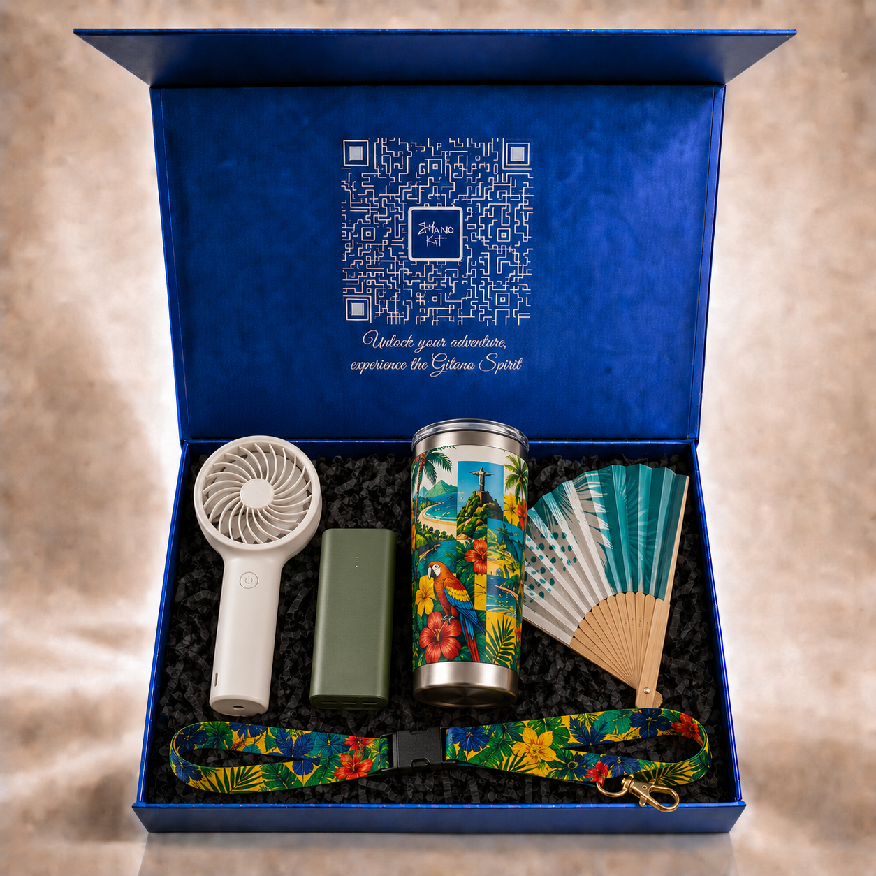 Sol &amp; Samba kit inside the open navy Gitano Kit gift box with QR-code lid and 'Unlock your adventure' script — turbo fan, power bank, tropical tumbler, folding hand fan and lanyard
