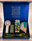 Sol & Samba kit inside the open navy Gitano Kit gift box with QR-code lid and 'Unlock your adventure' script — turbo fan, power bank, tropical tumbler, folding hand fan and lanyard